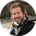 Smiling middle aged man with a beard wearing SCUBA gear.