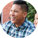 Smiling man holding a guitar with his young daughter smiling next to him.